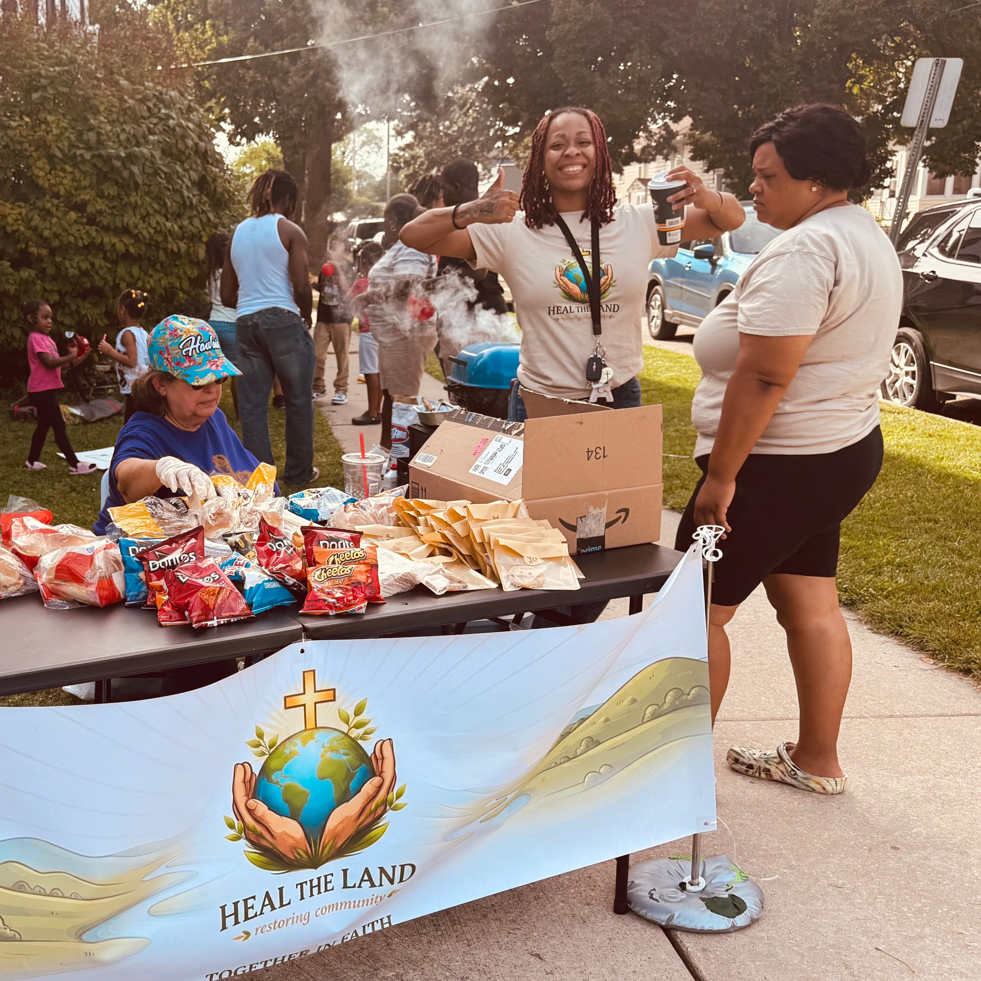 A volunteer giving a thumbs up behind the Heal the Land serving table