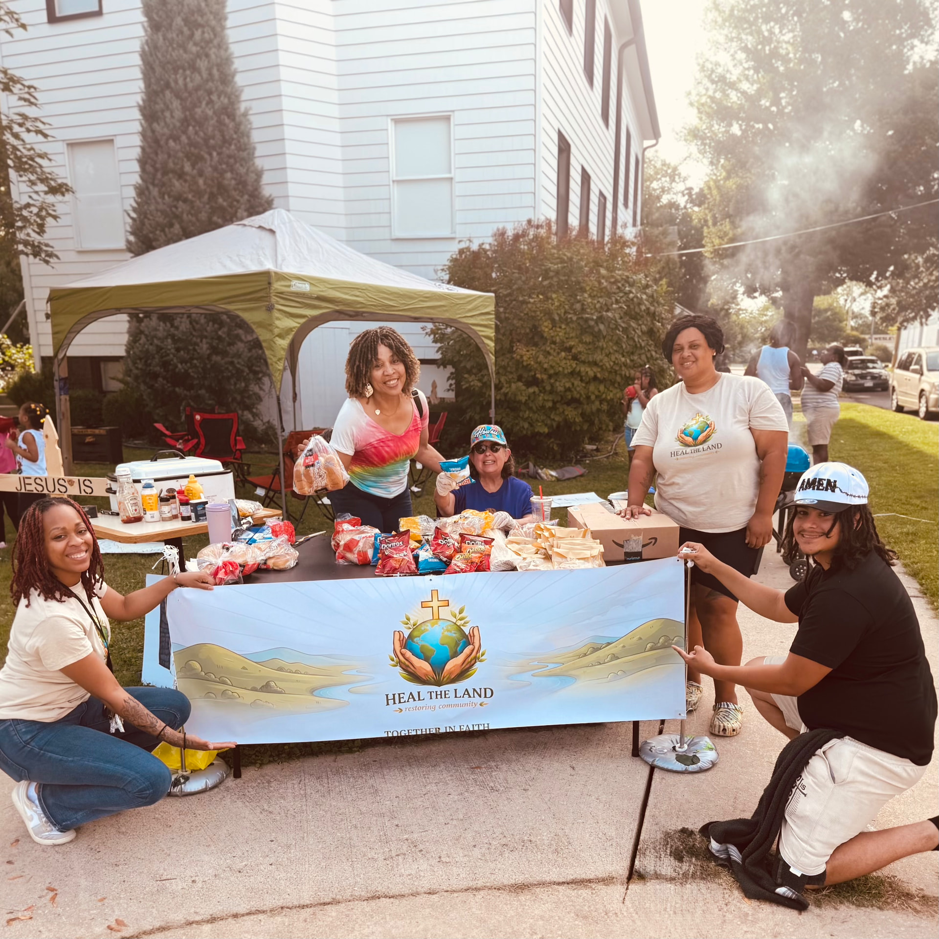 The Heal the Land team kneeling with their banner in front of the tent
