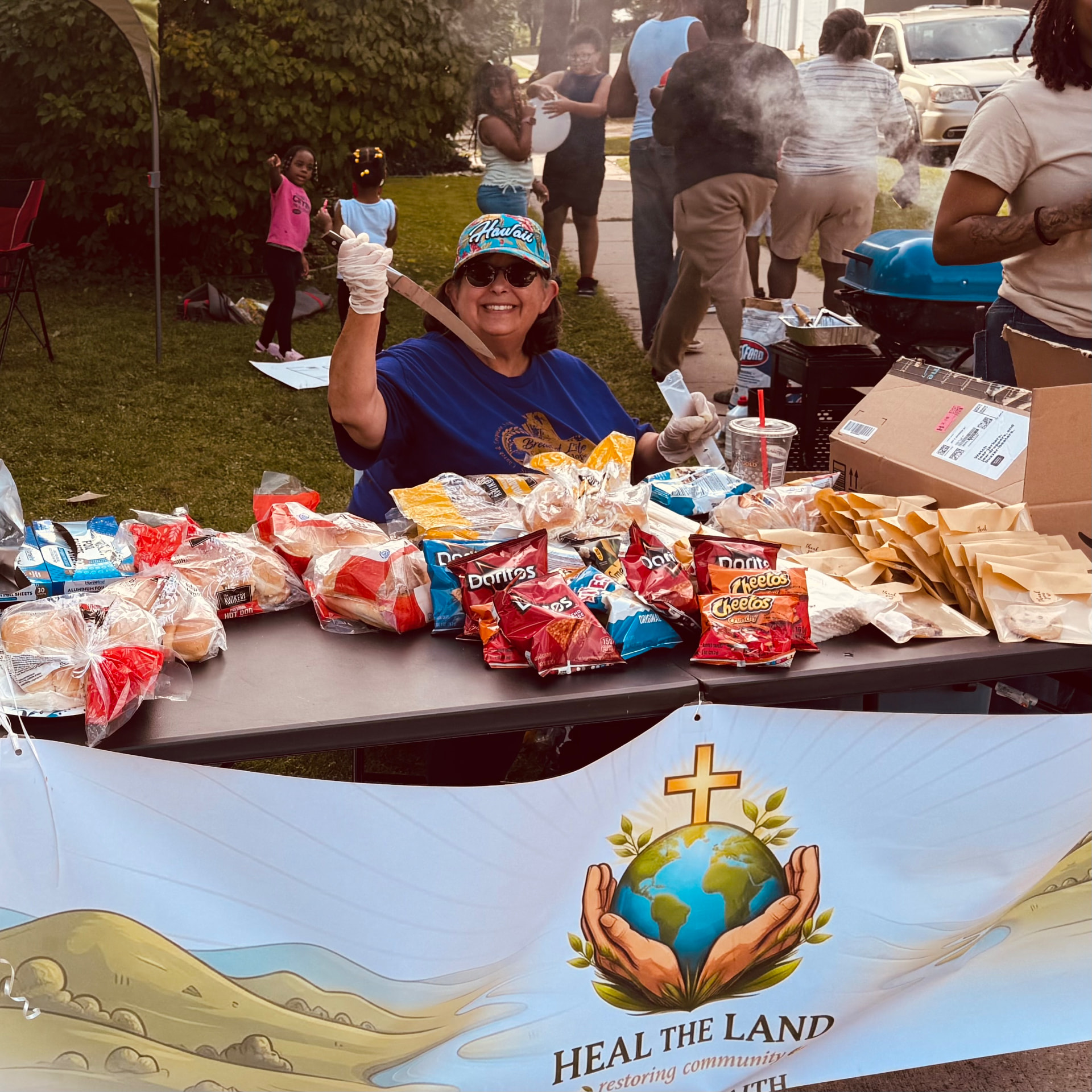 A smiling volunteer serving food at the Heal the Land table