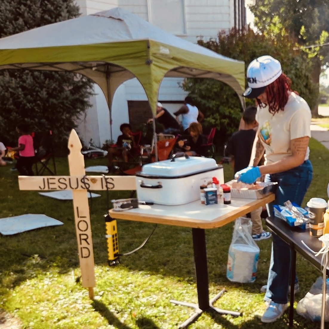 A hand painted Jesus Is Lord cross beside the grill and serving table